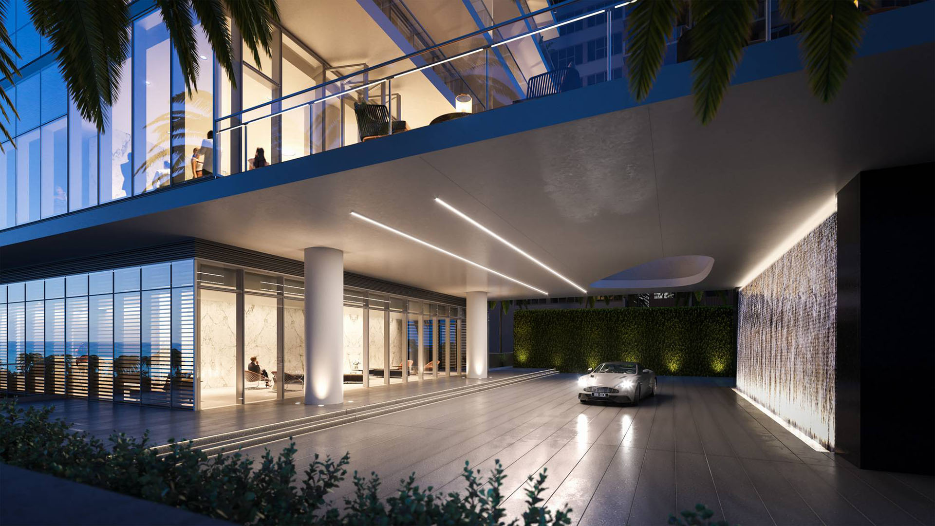 2000 Ocean, Hallandale Beach, Florida, porte-cochere arrival at night with waterfall wall, palms and bright lobby, promoting luxury and ultra luxury preconstruction condos.