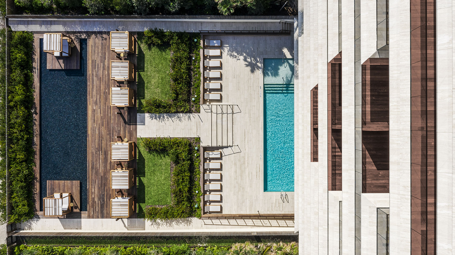 Vertical aerial of Arte Surfside, Surfside, Florida, featuring luxury and ultra luxury condos with a lap pool, cabanas, lounge chairs, and landscaped amenity terraces.
