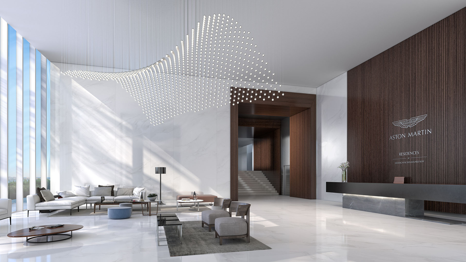 Aston Martin Residences in Downtown Miami luxury and ultra luxury condos grand lobby with a wave-like chandelier, marble floors, lounge seating, and a sleek reception desk.