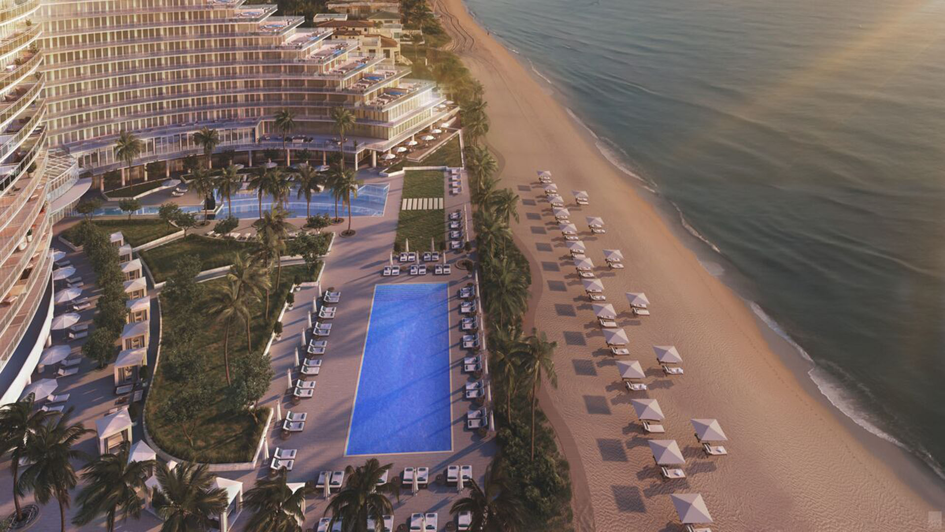 Auberge Beach Residences, Fort Lauderdale luxury and ultra luxury condos aerial view of a long beachfront pool deck with rows of cabanas, palm trees, and a quiet sandy shoreline beside the ocean.