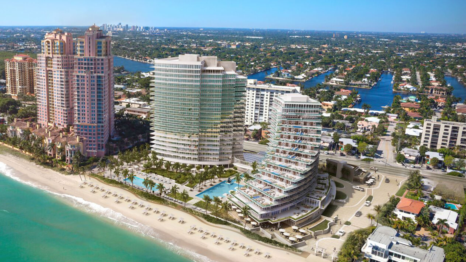Auberge Beach Residences, Fort Lauderdale luxury and ultra luxury condos aerial waterfront view of curved beachfront towers, pools, the sandy beach, and surrounding coastal waterways.