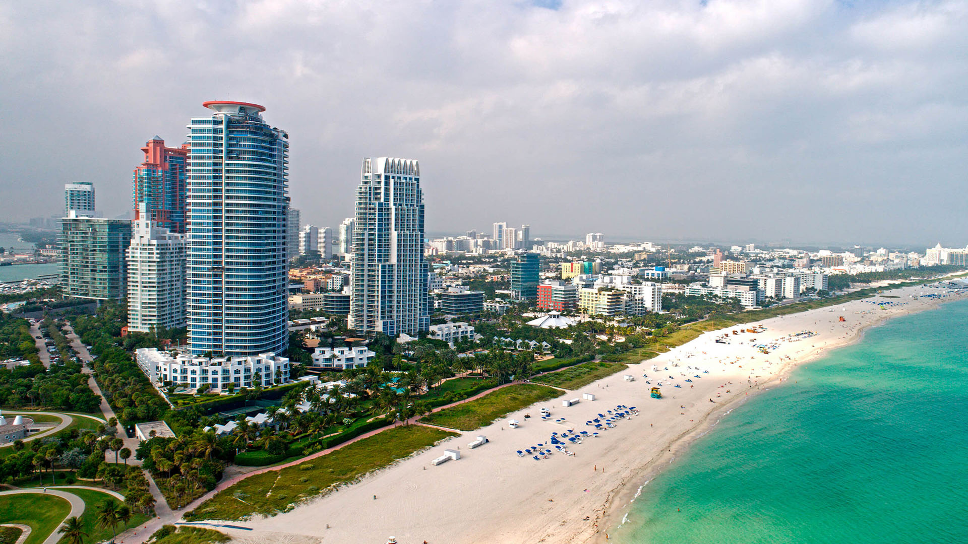 Aerial beachfront view of Continuum on South Beach, Miami Beach, Florida, showing luxury and ultra luxury condos along the white-sand shoreline with turquoise water and the South Beach skyline extending into the distance.