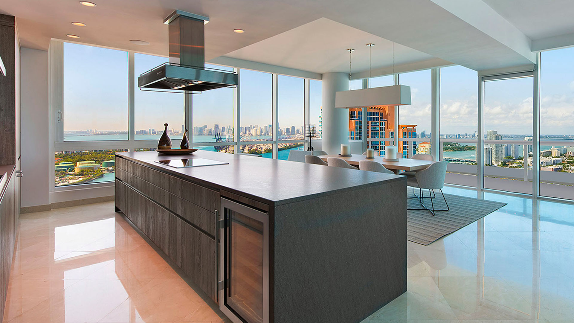 Chef kitchen at Continuum on South Beach, Miami Beach, Florida, inside luxury and ultra luxury condos, featuring a large island, dining area, and panoramic skyline and water views through corner glass.