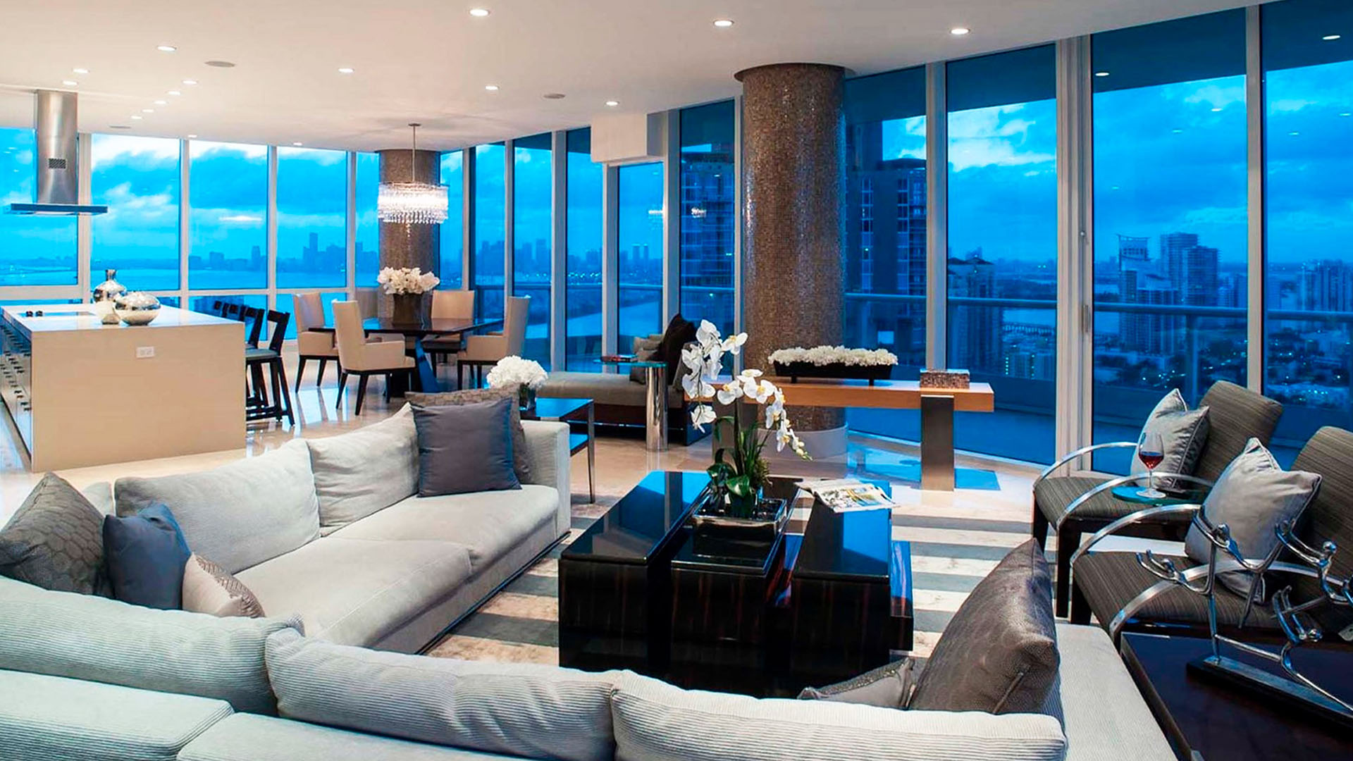 Open-plan living and dining area at Continuum on South Beach, Miami Beach, Florida, presenting luxury and ultra luxury condos with floor-to-ceiling glass, a modern kitchen, and an evening skyline view.