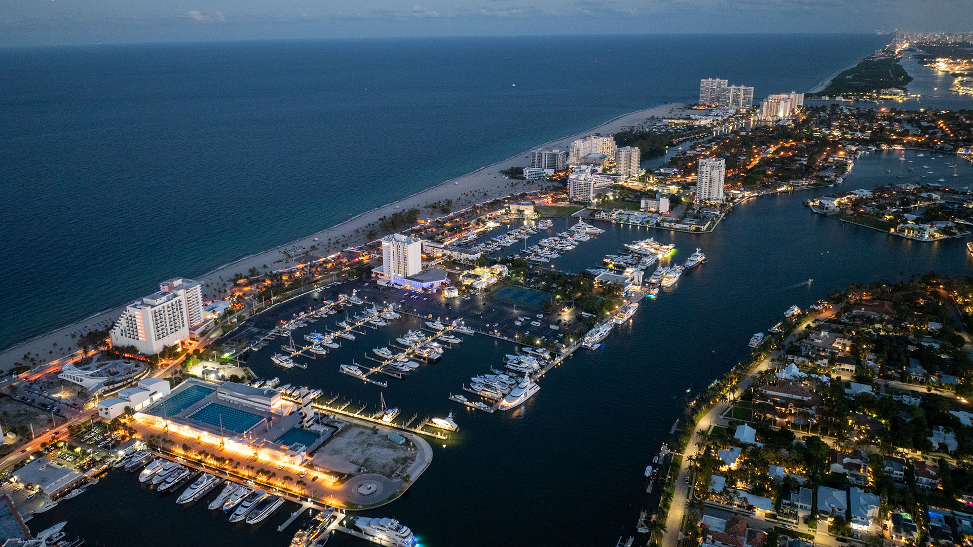 Aerial night view of Fort Lauderdale overlooking Bahia Mar marina, yachts and beachfront, showcasing luxury and ultra luxury preconstruction condos on the Intracoastal Waterway.