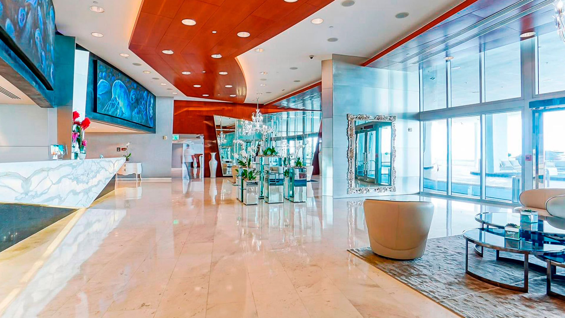 Grand lobby seating area at Jade Ocean in Sunny Isles Beach for the luxury and ultra luxury condos, with reflective columns, polished stone floors, designer seating, and glass entry doors.