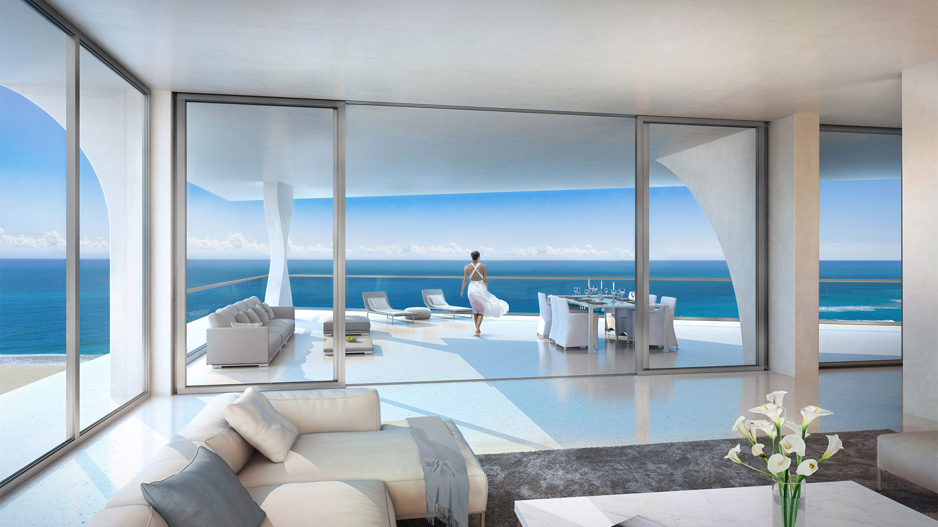 Jade Signature in Sunny Isles Beach luxury and ultra luxury condos living room opening to an expansive oceanfront terrace with lounge seating, dining table and wide water views.