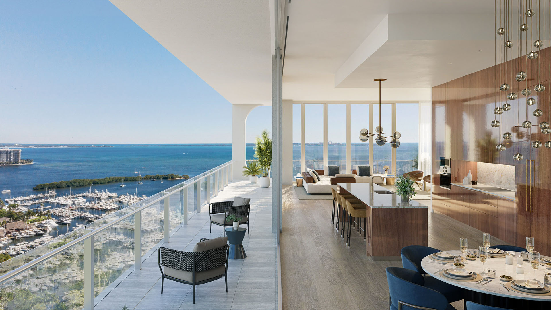 Chef kitchen with island seating, a round dining table, and sweeping marina views at Mr C Residences Bayshore Tower in Coconut Grove, showcasing luxury, ultra luxury condos with wraparound waterfront exposure.