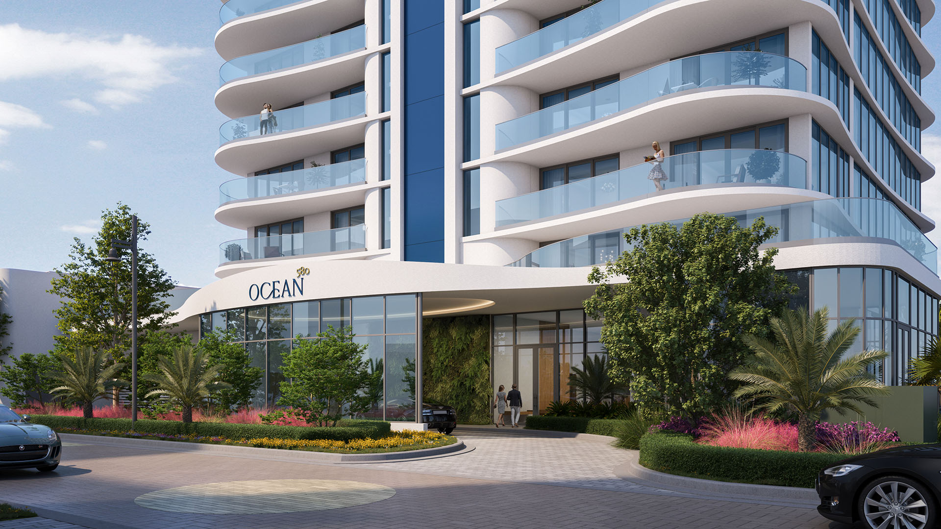 Daytime entrance at Ocean 580 in Pompano Beach, preconstruction luxury and ultra luxury condos with curved glass balconies, a porte cochere driveway, landscaped planting beds and a modern lobby frontage.