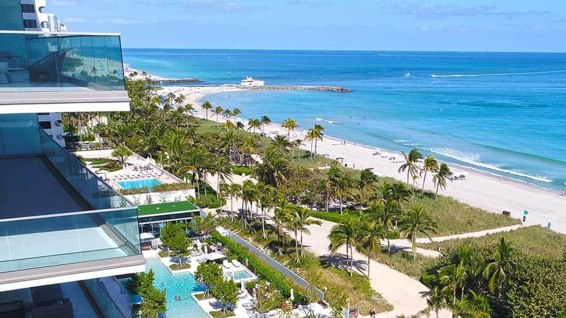 Aerial waterfront view of beachfront pools, landscaped grounds and the shoreline at Oceana Bal Harbour in Bal Harbour, Florida, highlighting the luxury oceanfront setting of these ultra luxury condos.