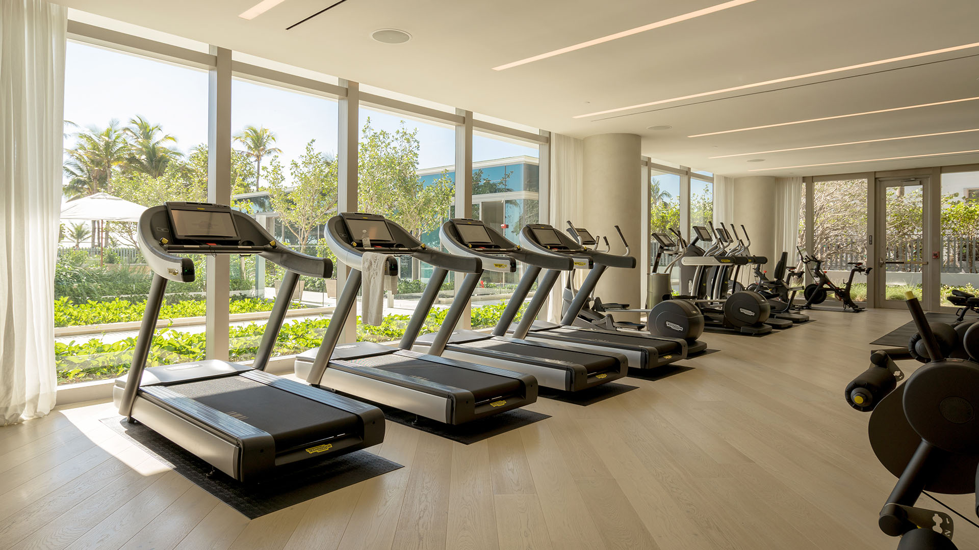 Fitness center with treadmills, cardio equipment and garden facing windows at Oceana Bal Harbour in Bal Harbour, Florida, extending the luxury wellness amenities of these ultra luxury condos.