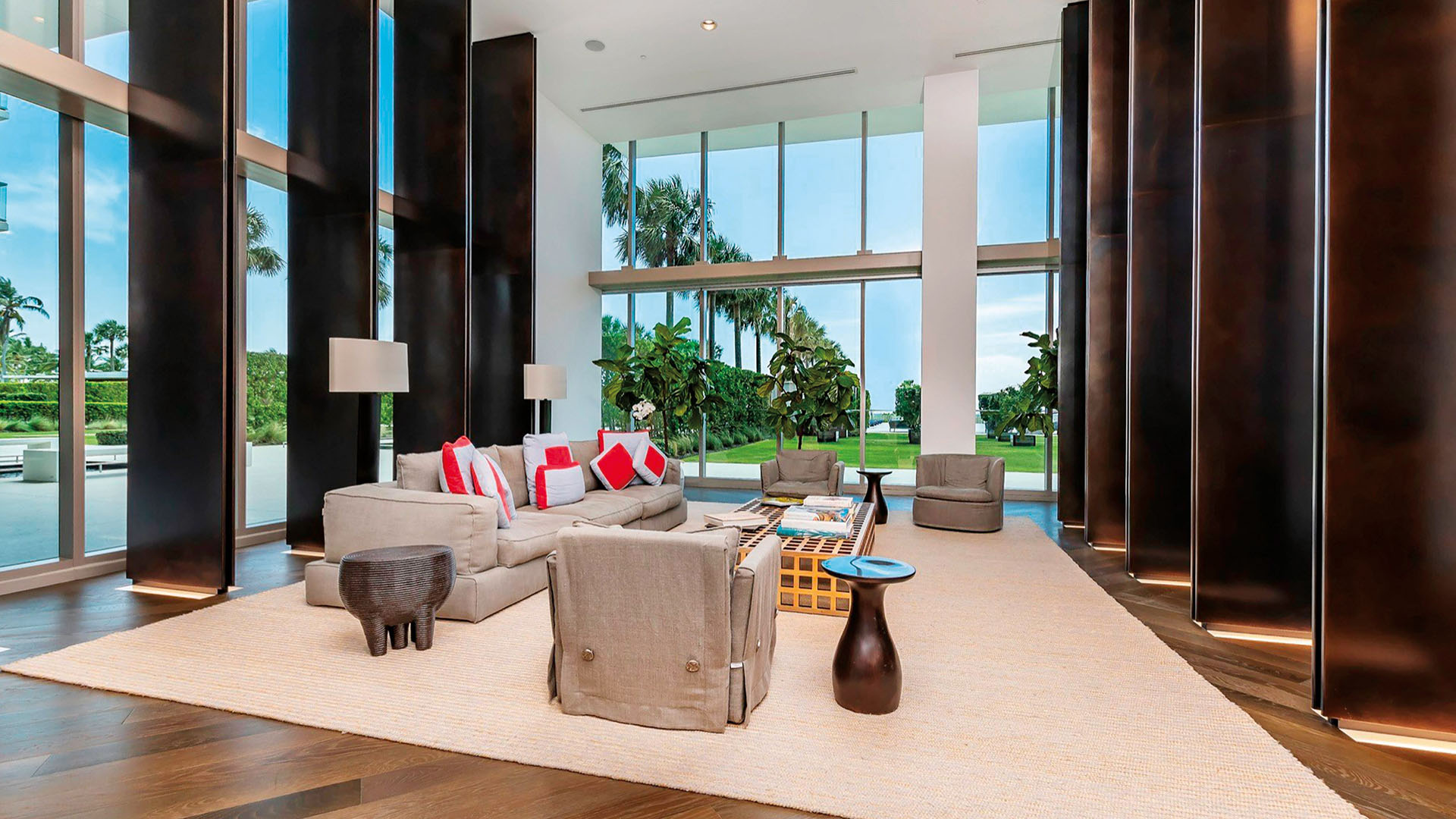 Double-height lobby lounge at Oceana Key Biscayne in Key Biscayne, presenting luxury and ultra luxury condos with tall windows, dark wood columns, soft seating, and garden views.
