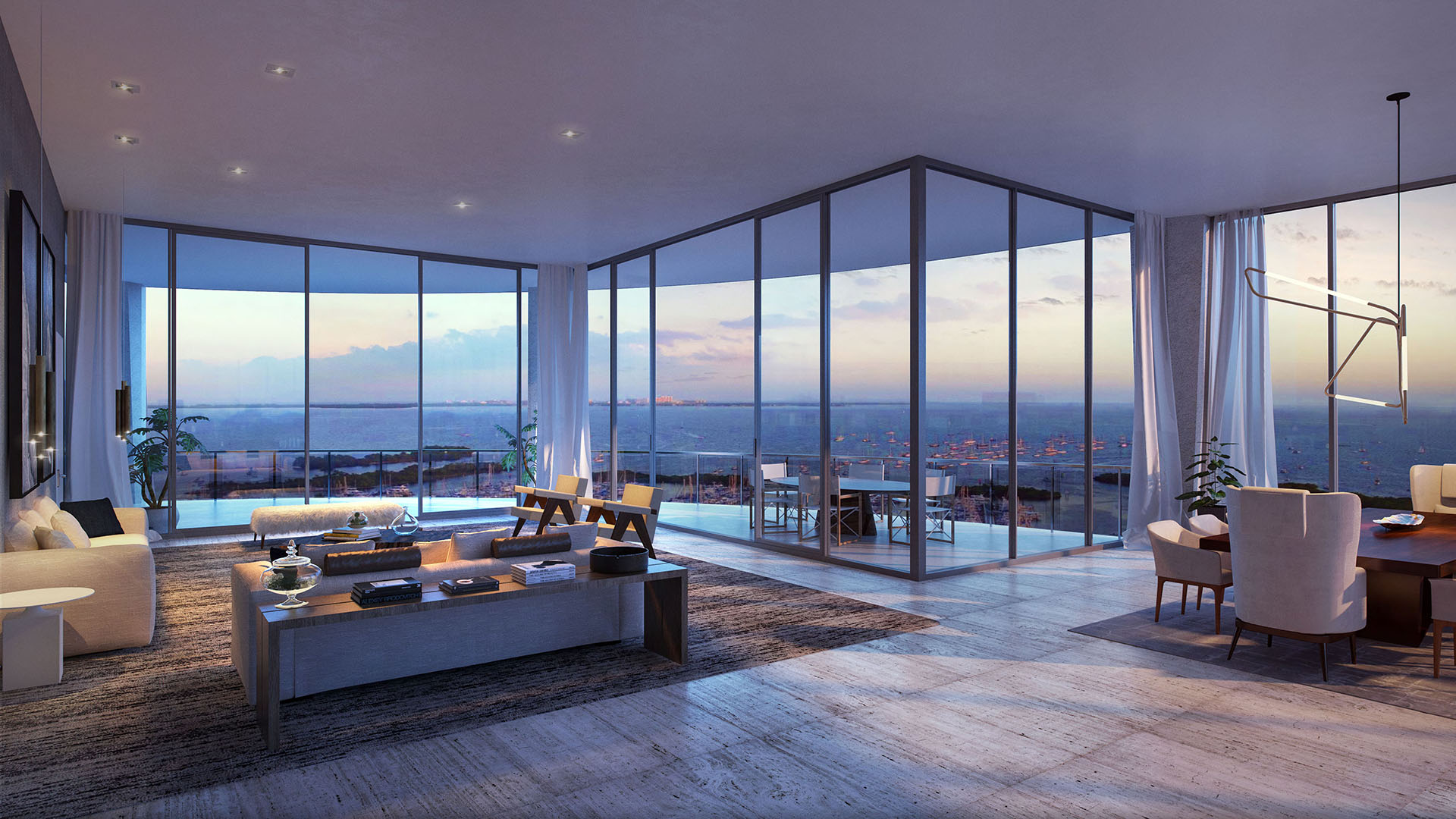 Corner great room with wraparound glass, a dining area and glowing dusk water views at Park Grove in Coconut Grove, showcasing luxury and ultra luxury condos interiors.