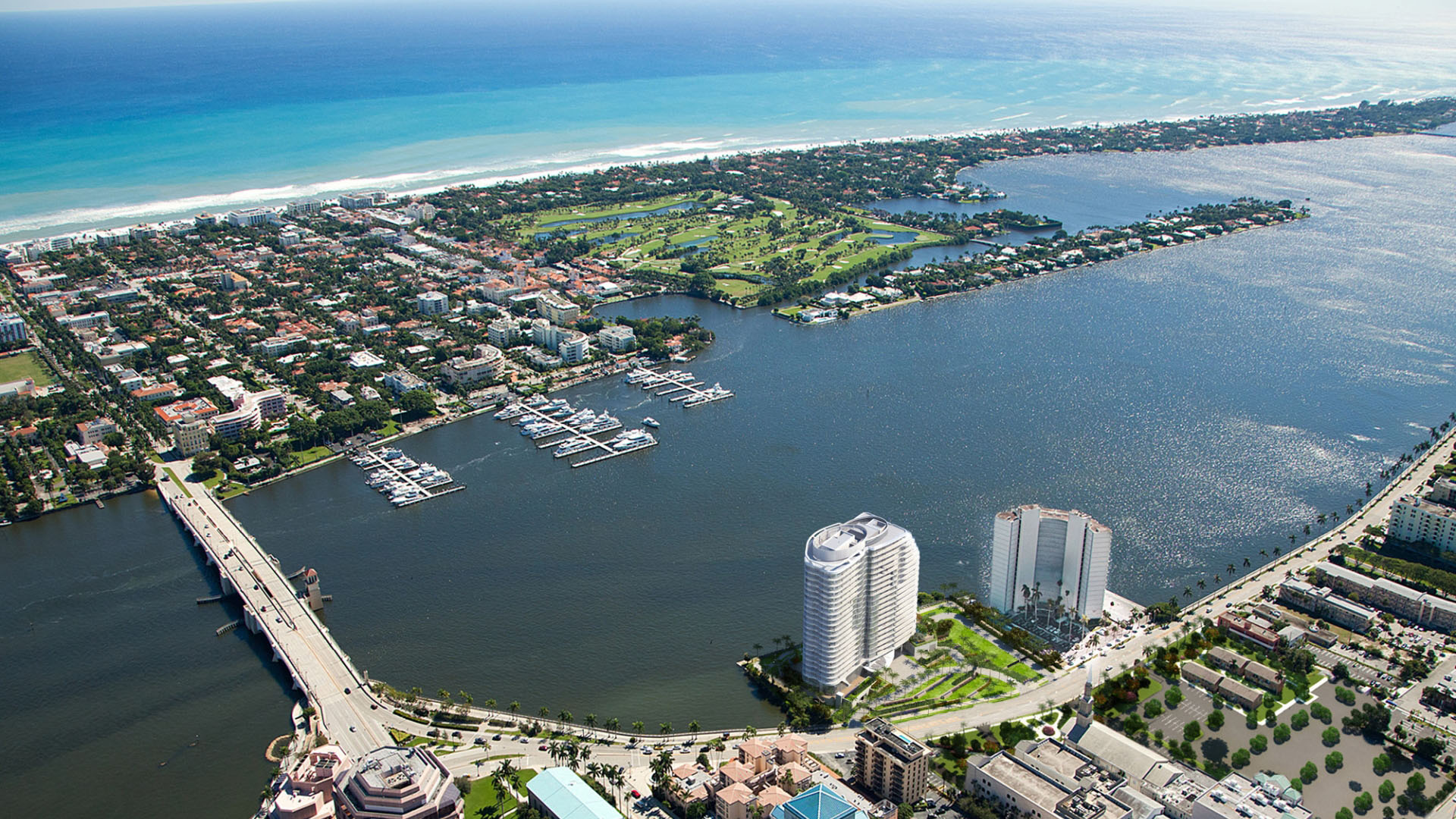 High aerial of coastline, golf course, marina, and a waterfront tower at The Bristol Palm Beach in Palm Beach, highlighting luxury and ultra luxury condos beside ocean and waterway views.