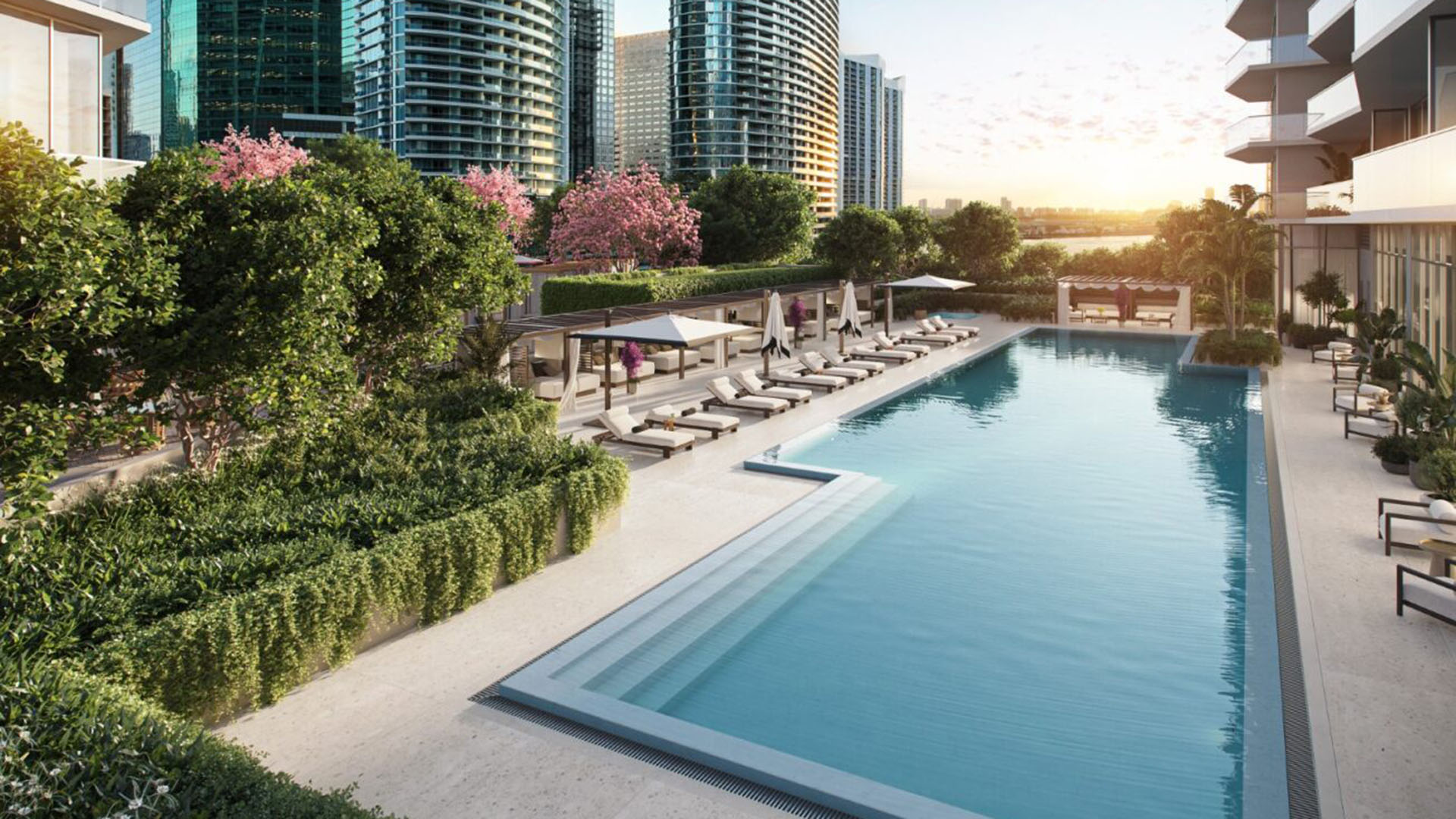 Viceroy Brickell The Residences in Brickell, Miami, luxury and ultra luxury preconstruction condos with a resort pool terrace, sun loungers, cabanas, lush landscaping, and a sunset waterfront backdrop.